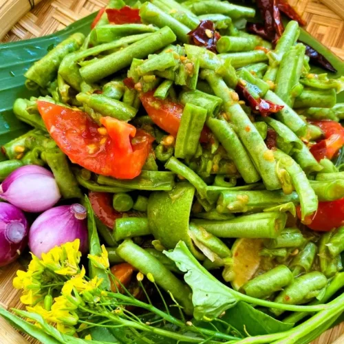 Thai long bean salad, known as som tum tua, with yardlong beans, lime, and ripe tomatoes on a bamboo basket.