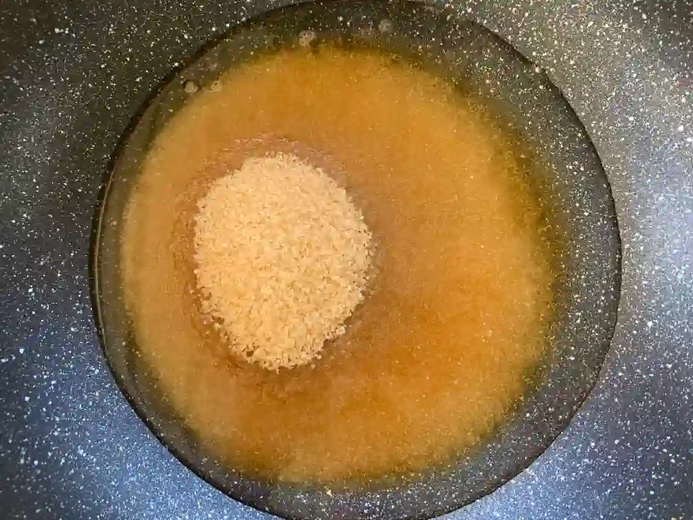 Water with brown sugar in a wok.