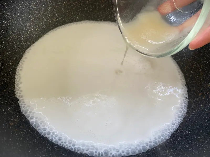 Adding soaked agar-agar mixture to coconut milk for the jelly layer.