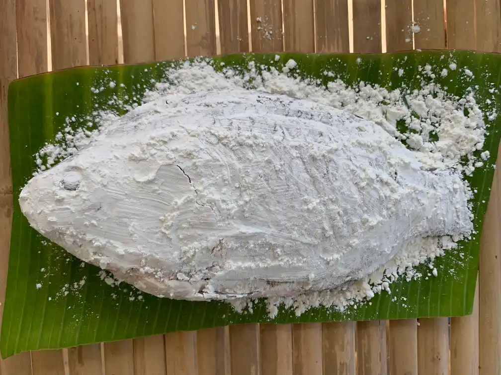 Top-view of cornflour coated whole fish on a banana leaf.