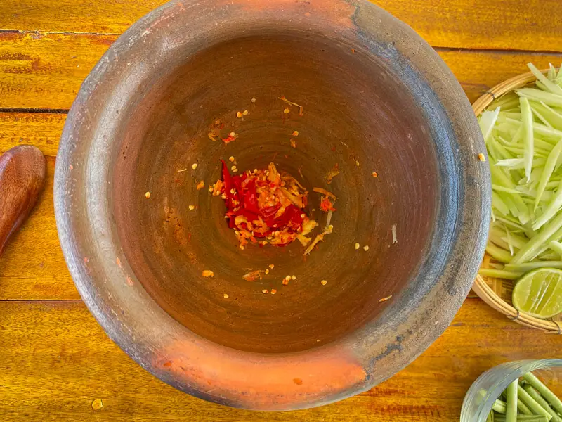 Garlic and chilies crushed in a mortar and pestle.