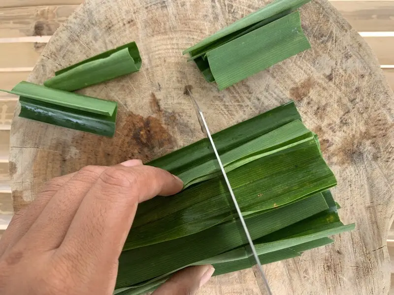 Cutting fresh pandan leaves into small pieces.