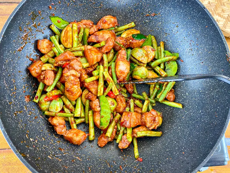The completed Thai red curry stir-fry with juicy pork, vibrant green beans, and Thai eggplants in a glossy sauce.