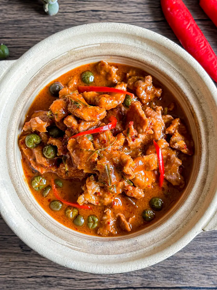 Bowl of Thai panang curry pork with green peppercorns and red chili.