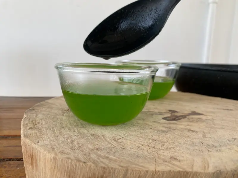 Pouring pandan jelly layer into small cups to set.
