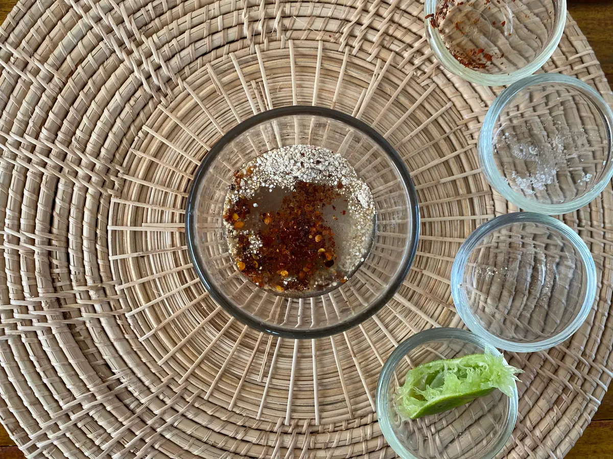 Large glass cup containing ingredients for making this Thai condiment. Around it are empty glass cups.
