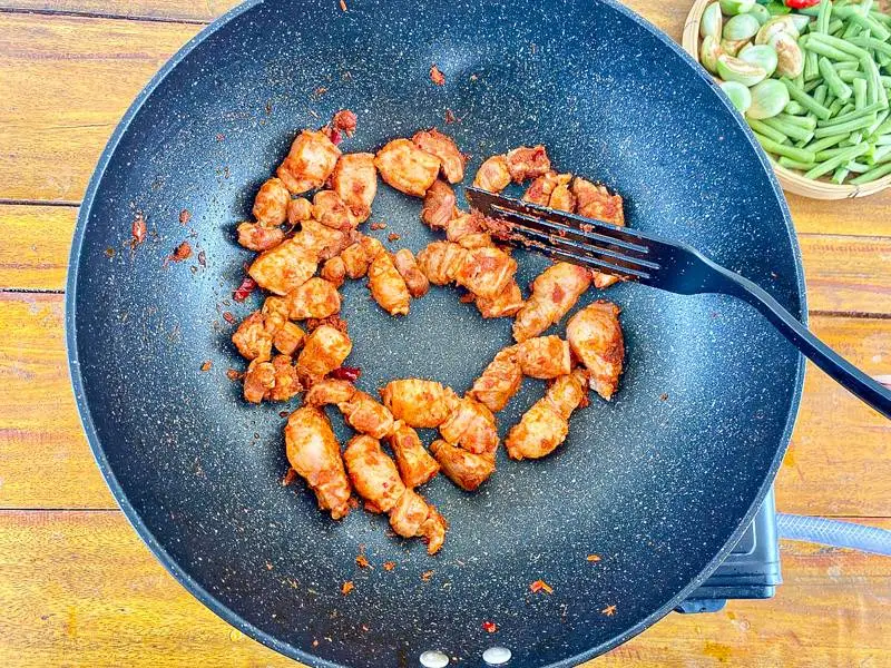 A bamboo tray with chopped yardlong beans, sliced Thai eggplants, red chilies, and hand-torn kaffir lime leaves.
