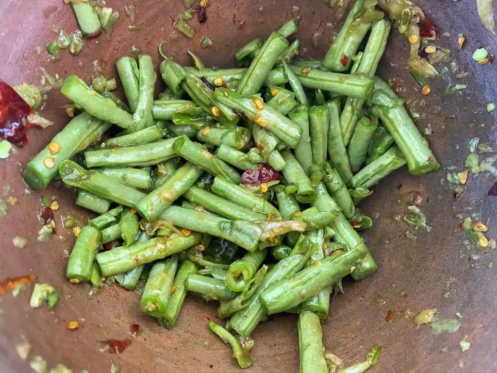 Seasoned yardlong beans in a clay mortar, infused with spices.