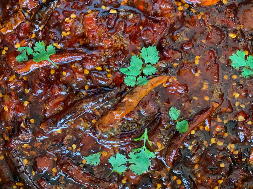 Close-up of Thai tamarind dipping sauce with dried chilies and coriander leaves.