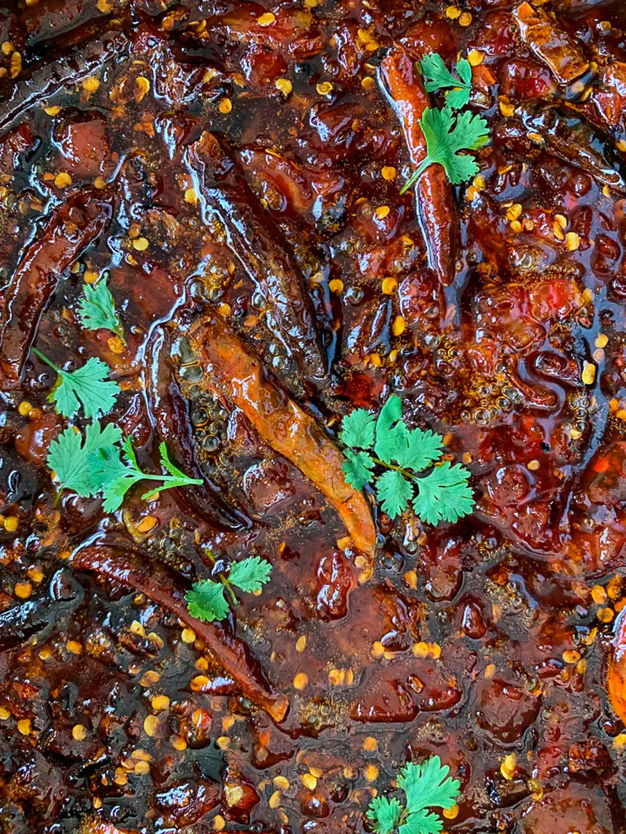 Close-up of spicy Thai tamarind sauce simmering with dried chilies and chili flakes.