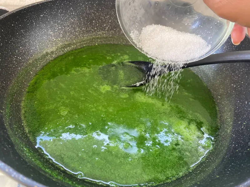 Adding sugar to pandan juice while cooking the jelly layer.