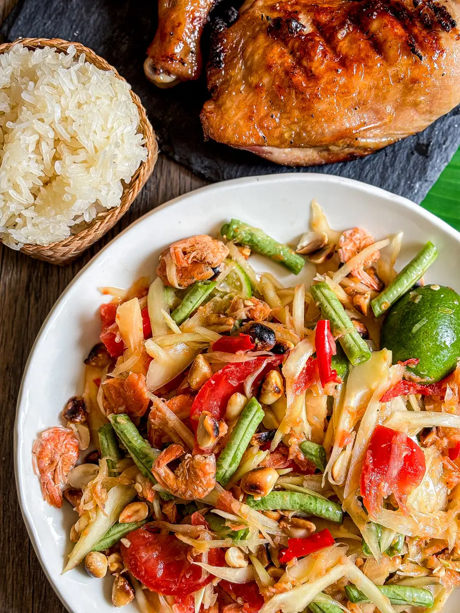 Som tam Thai papaya salad served with sticky rice and grilled chicken.