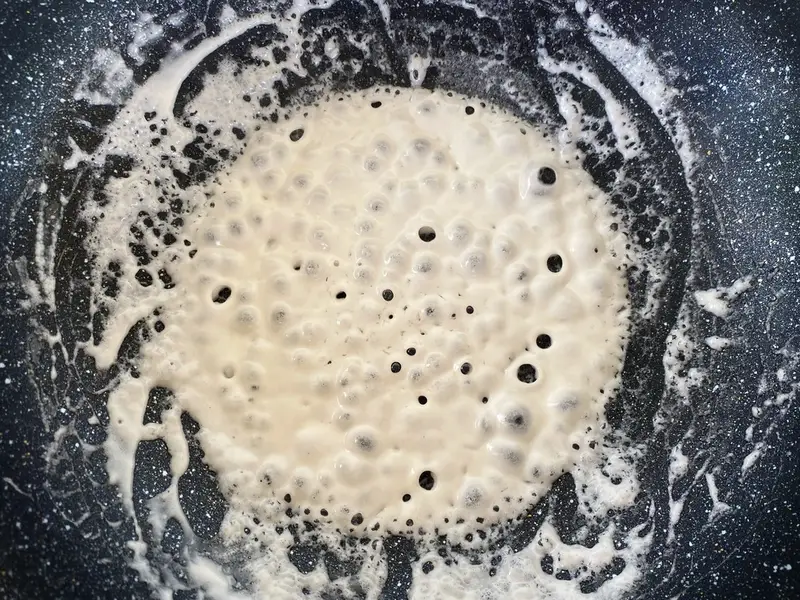 Coconut milk cooking in a pan with oil starting to separate.