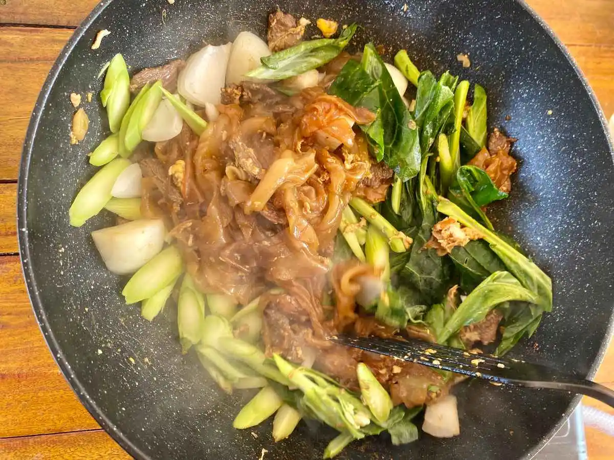 Finished pad see ew cooking in a wok.