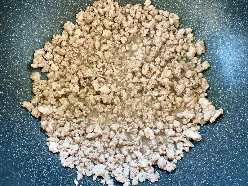 Ground pork cooking in a pan with its own juices.