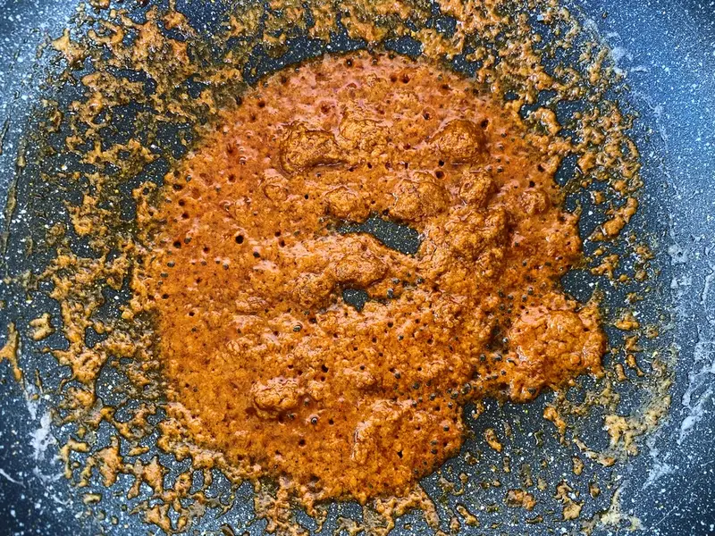 Massaman curry paste cooking in coconut milk in a pan.