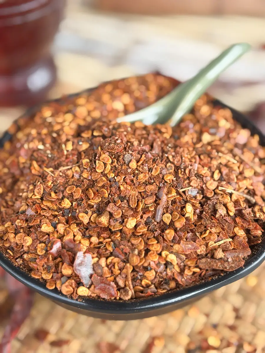 Bowl of homemade Thai chili flakes (prik bon) with visible seeds and toasted bits.