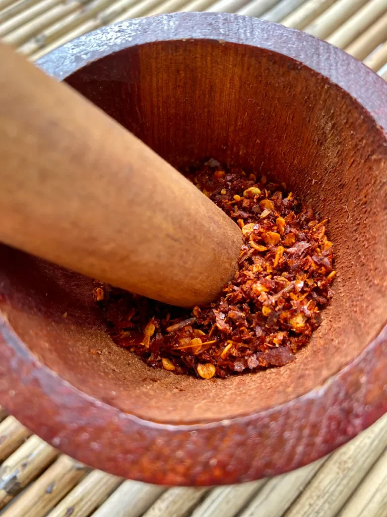 Close-up of Thai chili flakes in mortar with pestle.