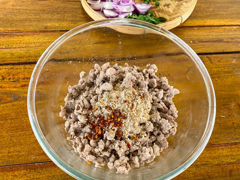 Cooked ground pork with chili flakes and toasted rice powder in a bowl.