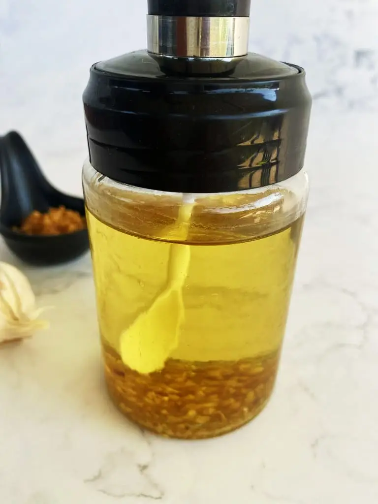 Fried garlic and garlic oil stored in a glass jar on a white background.
