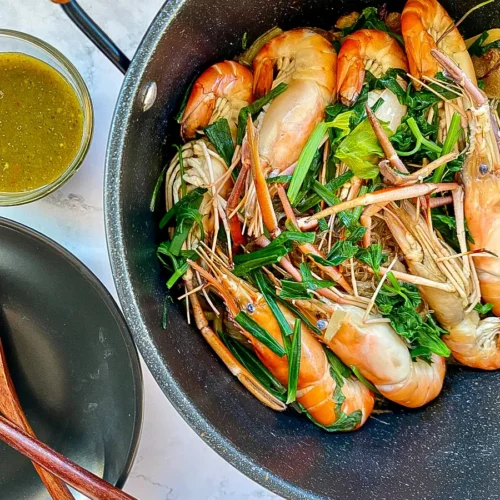 Goong ob woon sen in a pot, showcasing the layering of prawns on top of glass noodles with fresh greens, ready for serving.