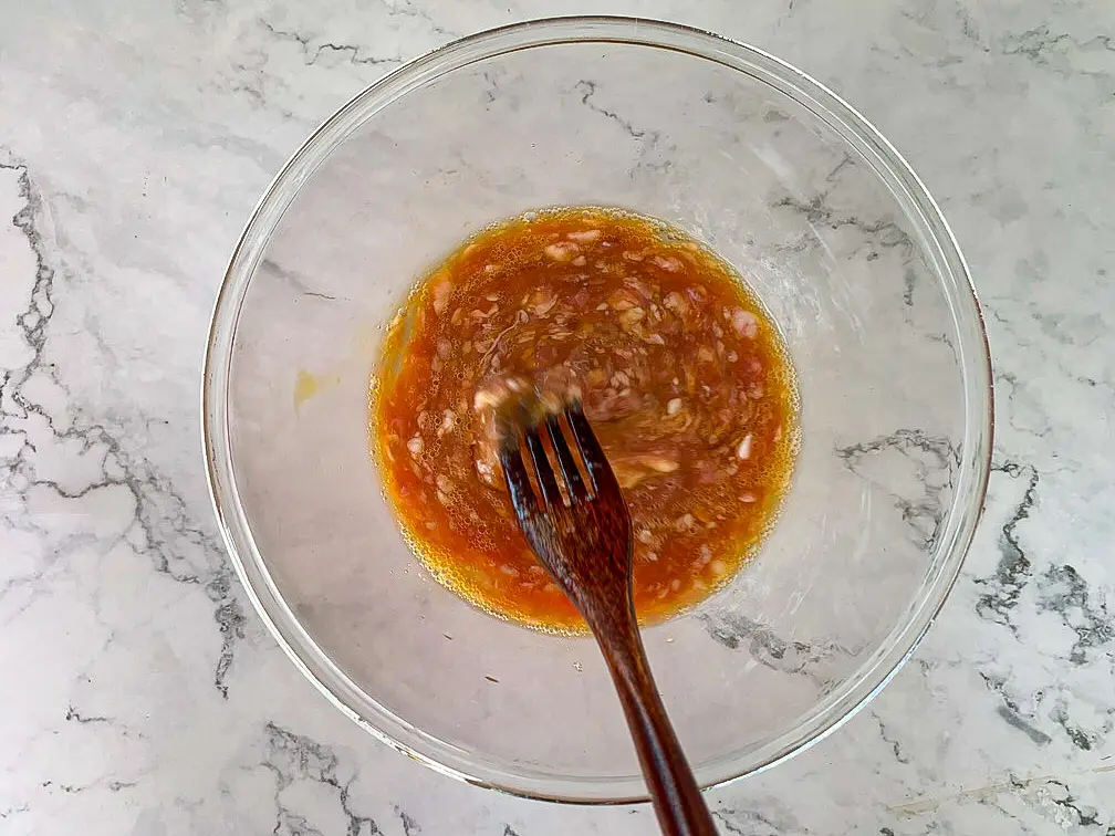 Mixing eggs, minced pork, and seasonings in a bowl.