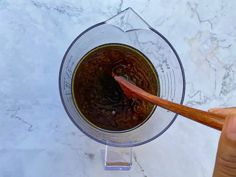 Mixing oyster sauce, dark soy sauce, sesame oil, and Thai seasonings in a bowl.