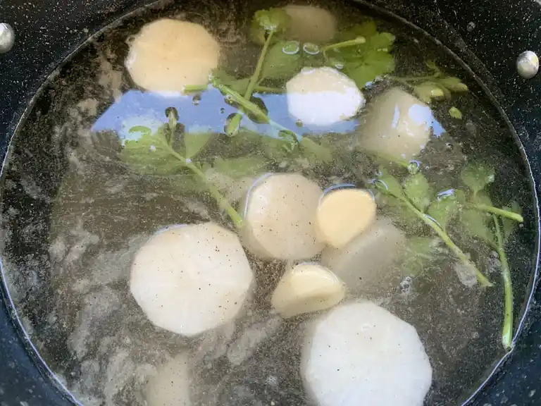 Mookata soup base in pot with radish, celery, and Thai seasonings.