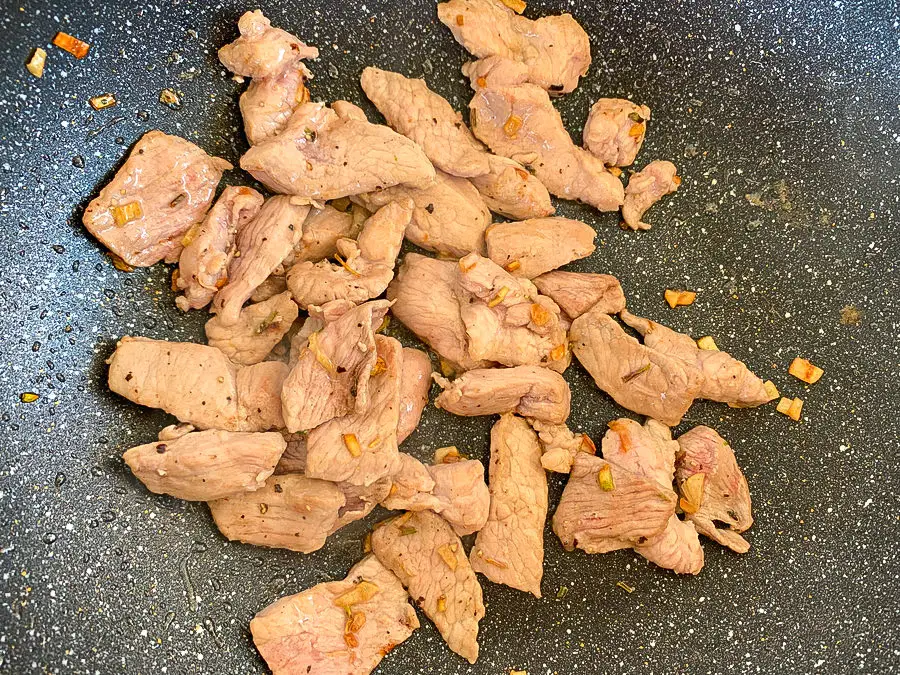 Sliced pork with garlic cooking in a wok.