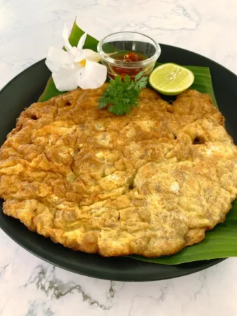 Thai minced pork omelette served on a banana leaf with lime and chili sauce.