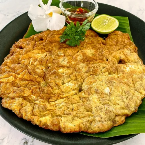 Thai pork omelette (kai jeow moo sab) served with fish sauce and lime.