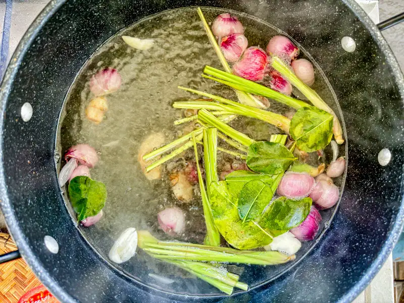 Lemongrass, kaffir lime leaves, galangal, and shallots simmering in broth.