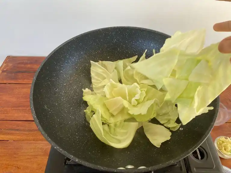 Stir-frying cabbage in a hot wok.