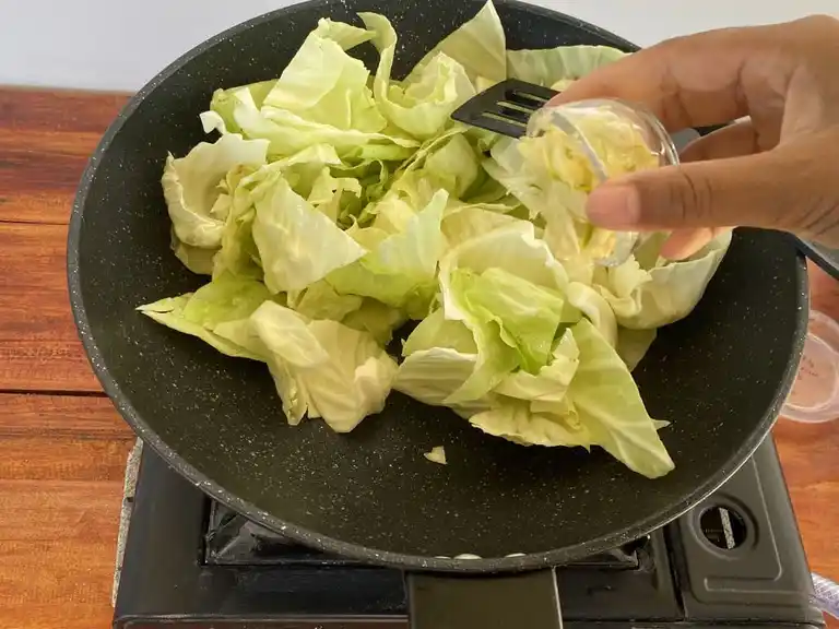 Infusing minced garlic into Thai cabbage stir-fry.