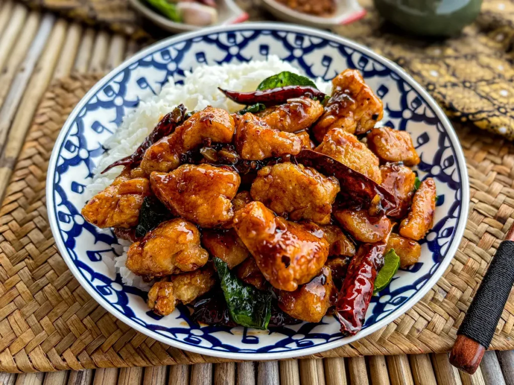Thai pad prik haeng, a spicy chicken stir-fry, served with white rice on a blue and white dish.