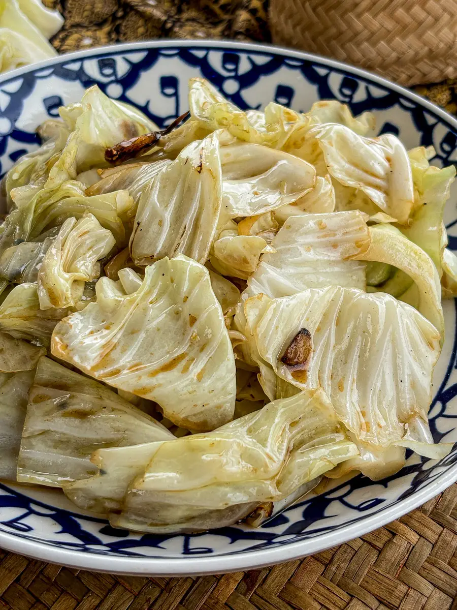 Close-up of Thai fried cabbage with seared edges and garlic pieces.