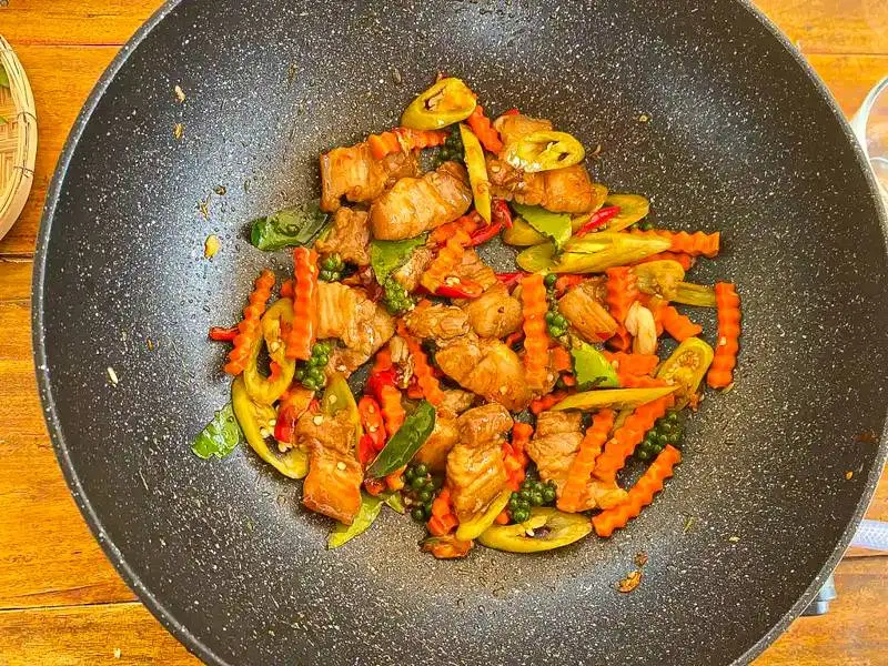 Vegetables and pork stir-frying in a wok.
