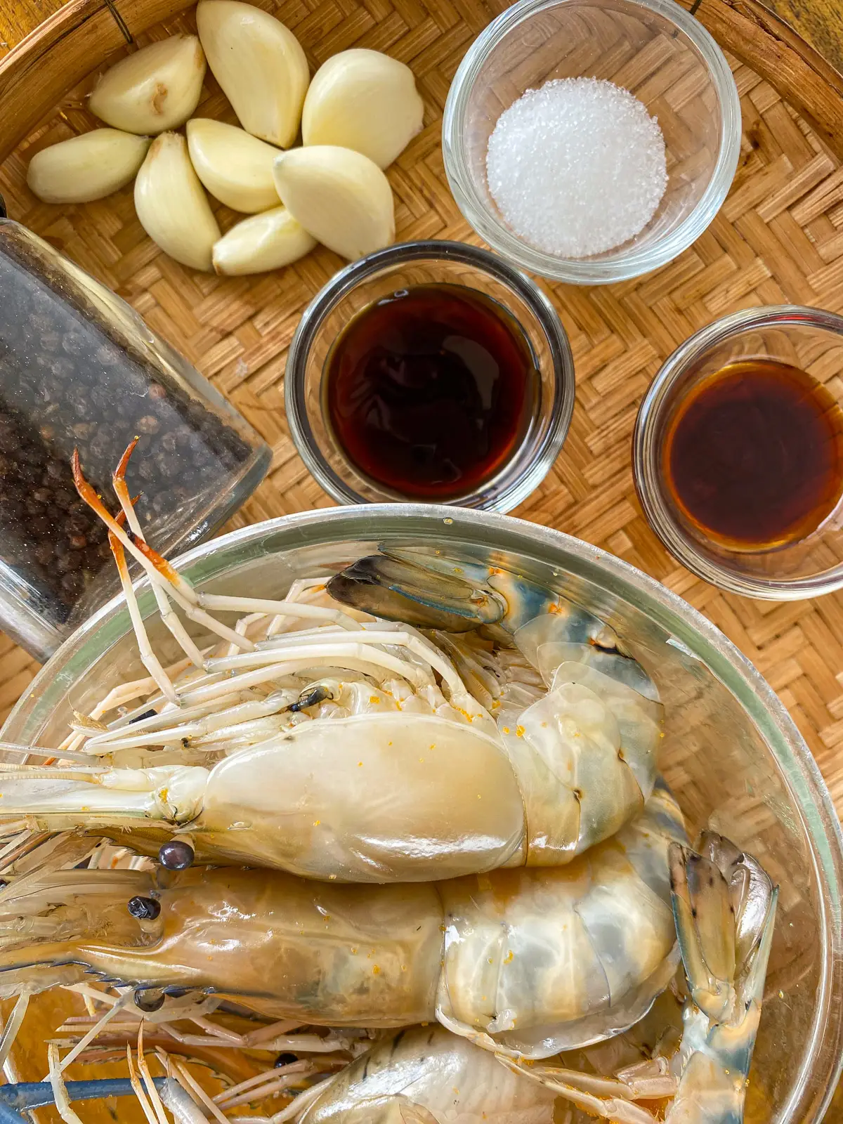 Ingredients for Thai crispy garlic prawns, including shell-on prawns, garlic, oyster sauce, soy sauce, sugar, and black pepper.