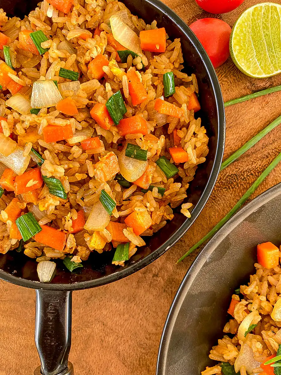 Fried rice with day old rice served in 2 black dishes.
