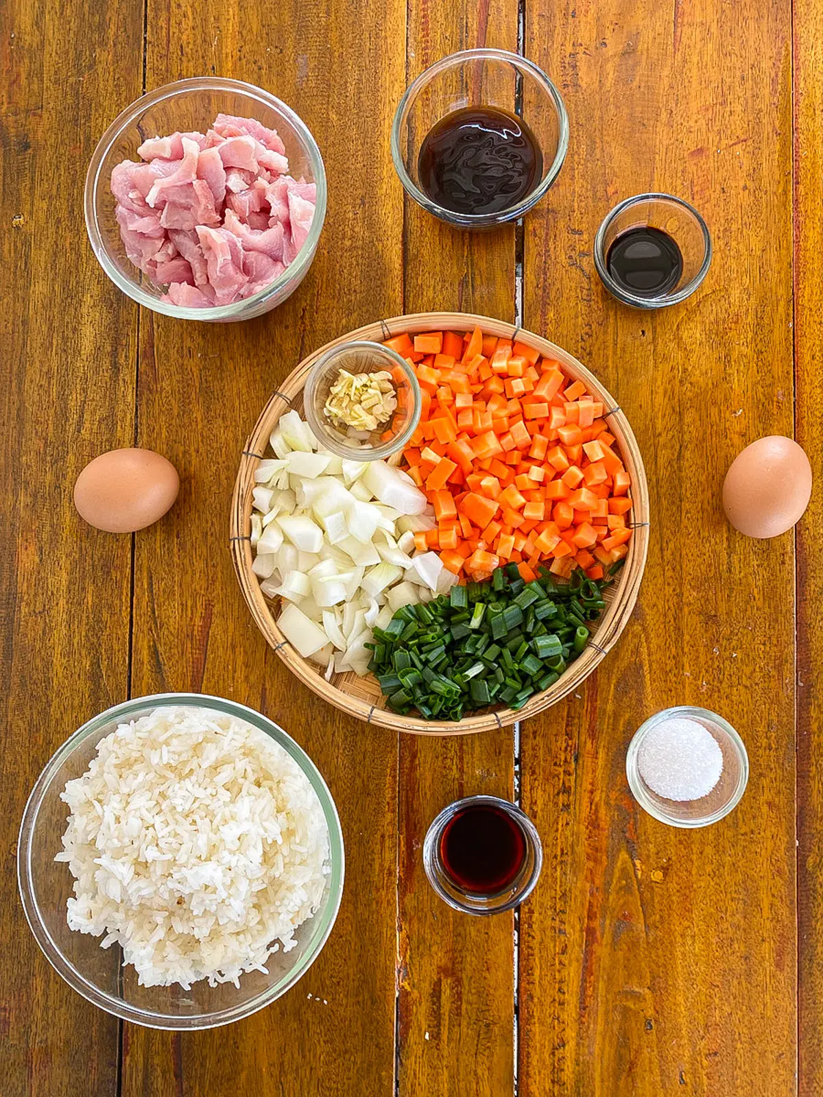 Ingredients for fried rice with day-old rice, including pork, eggs, carrots, onion, garlic, and jasmine rice.