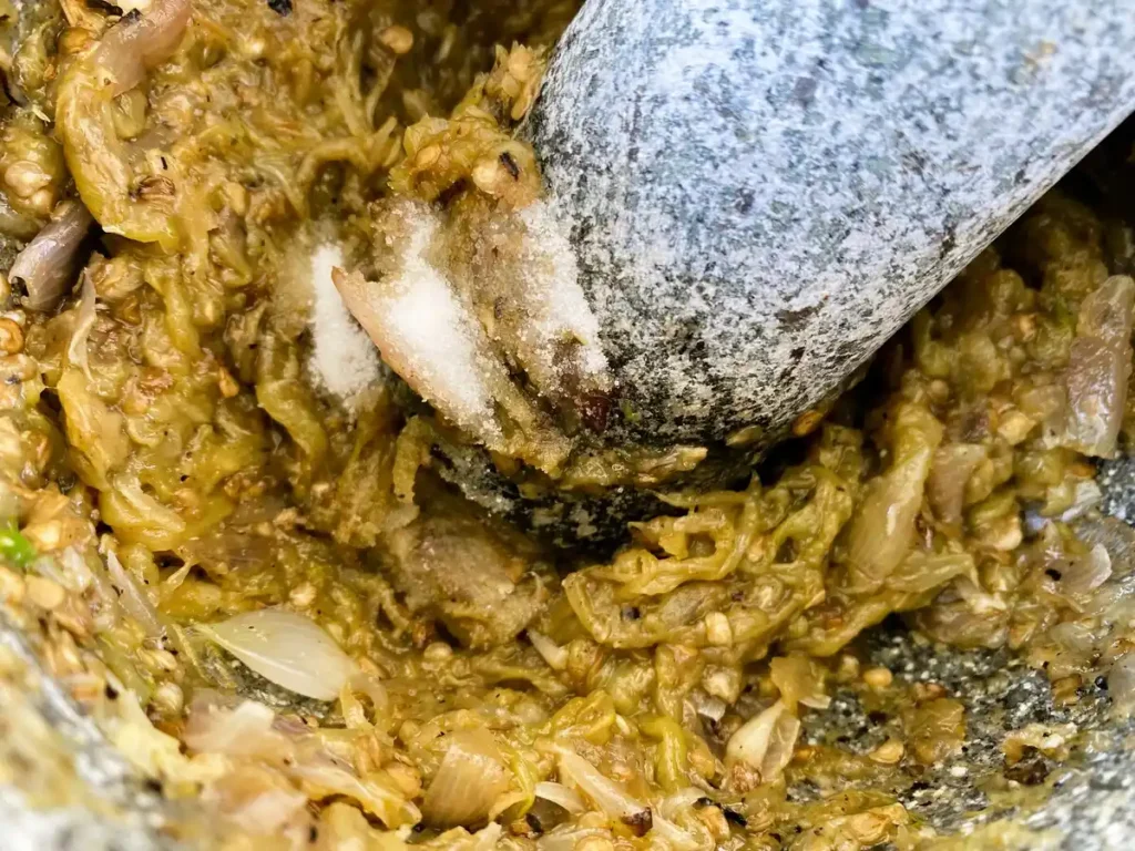 Making nam prik noom with a mortar and pestle.