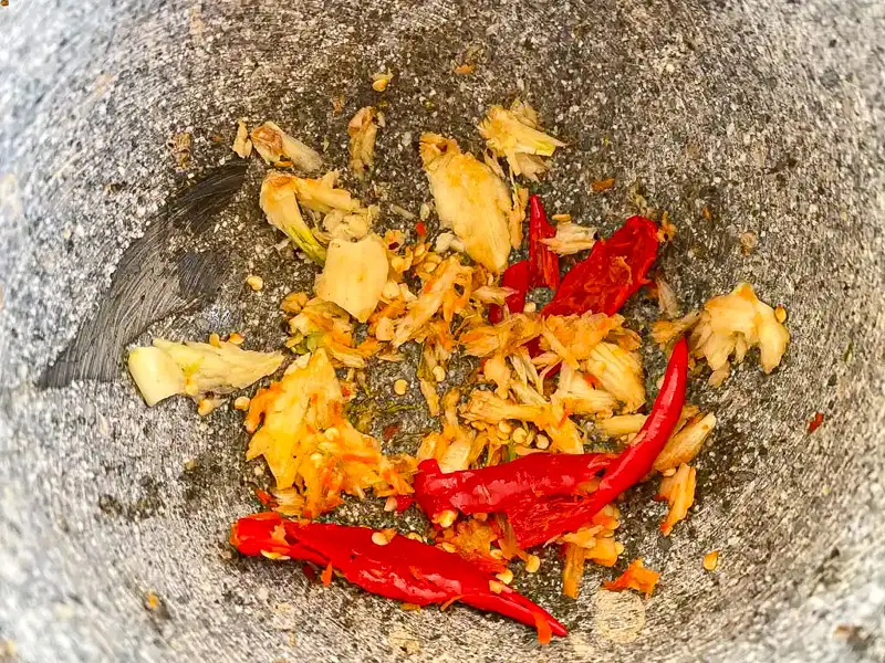 Garlic and chilies pounded in a granite mortar and pestle.