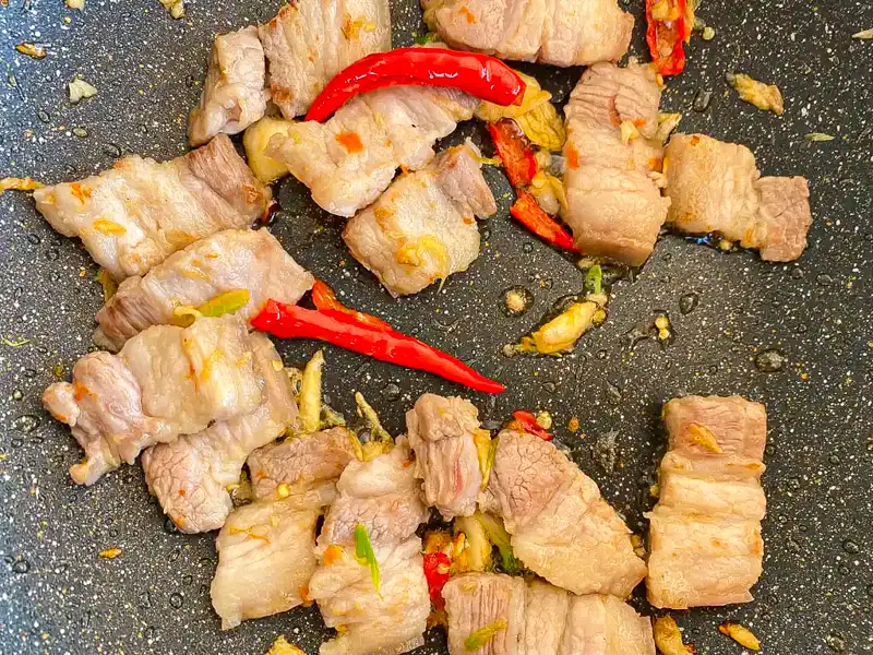 Stir-frying pork belly with garlic and fresh chilies.