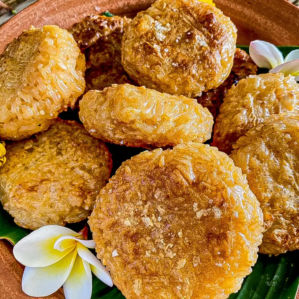 Thai khao jee—crispy egg-coated sticky rice patties—served with tropical floral decoration.
