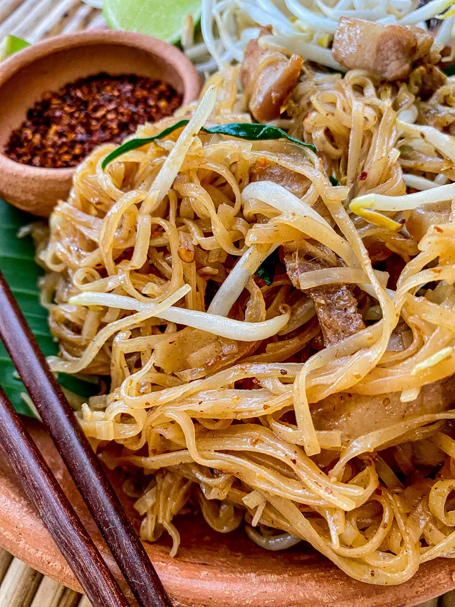 Close-up of pad mee korat showing chewy rice noodles coated in a spicy tamarind sauce.