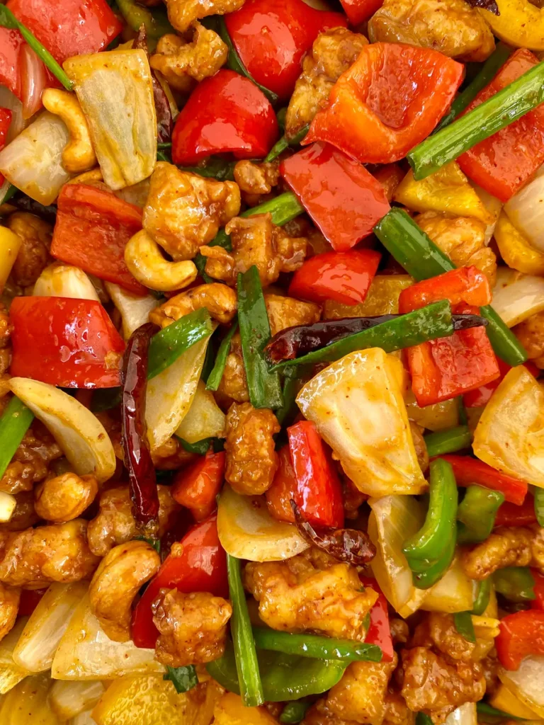 Close-up of gai pad med mamuang featuring colorful bell peppers, crunchy chicken, dried chilies, onions, and more.
