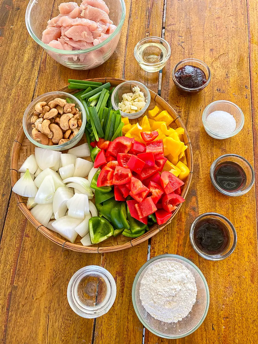 Fresh ingredients for gai pad med mamuang with chicken, cashews, vegetables, and Thai stir-fry sauces.