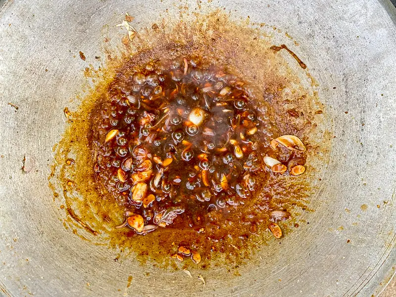 Pad mee korat sauce simmering with tamarind, palm sugar, fish sauce, garlic, and shallots.