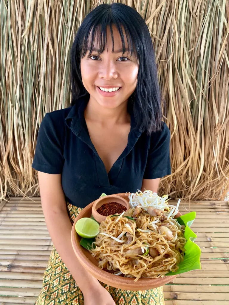 Praew serving homemade pad mee korat with pork belly, bean sprouts, and Thai chili flakes.