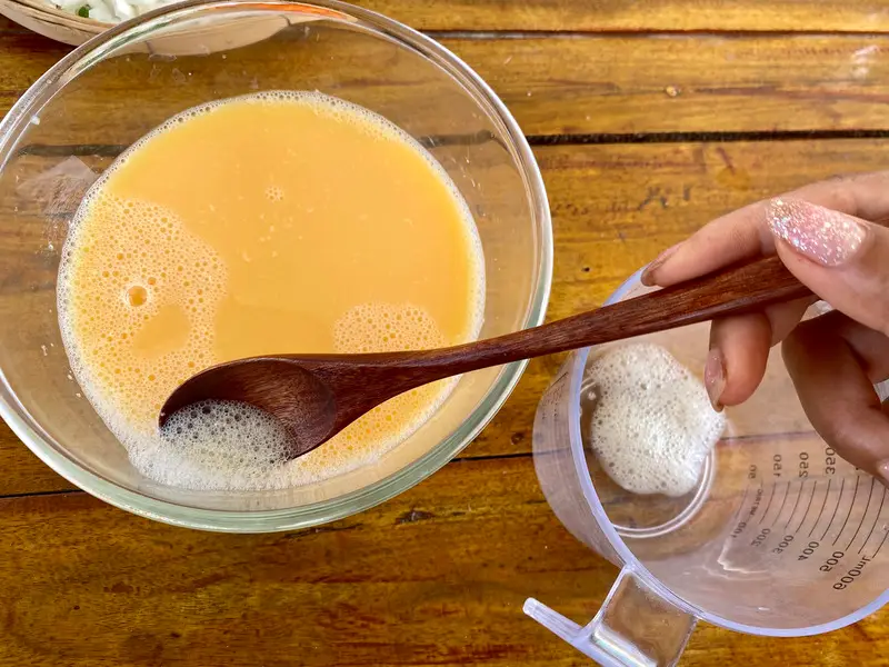 Skimming foam from the steamed egg mixture before steaming.